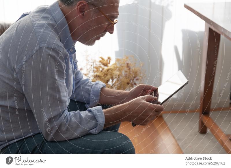 Älterer Mann benutzt Tablette auf Sofa benutzend digital Lügen ruhen heimwärts Apparatur Gerät sich[Akk] entspannen lässig männlich reif Browsen Internet Surfen