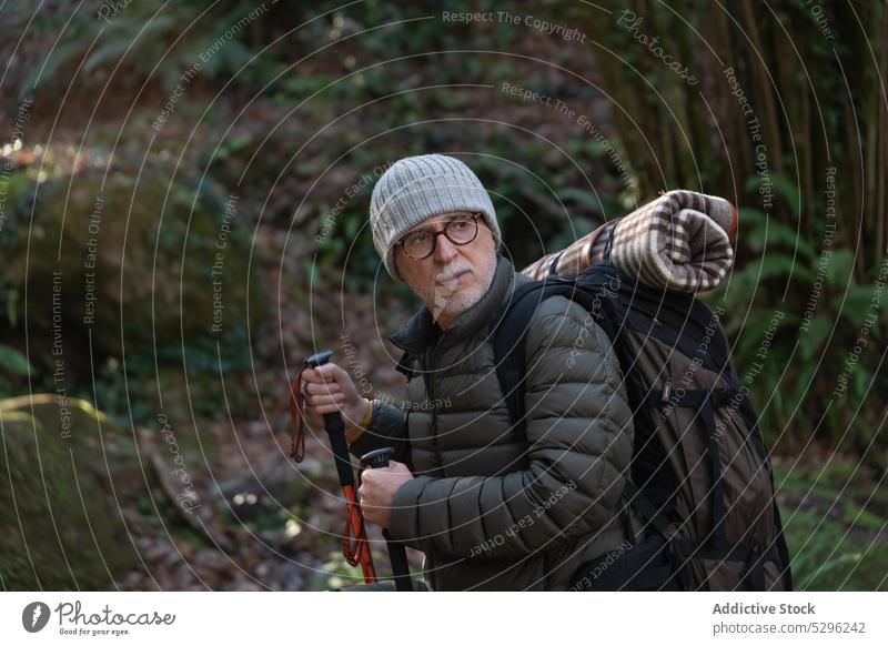 Älterer Reisender mit Rucksack und Trekkingstöcken im Wald Mann Wanderer Spaziergang Wanderung Natur erkunden Ausflug männlich Senior Abenteuer Mast reisen