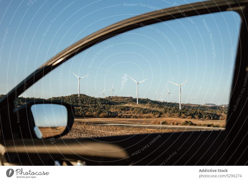 Ländliches Feld mit Windkraftanlagen PKW Fenster Fahrzeug Turbine Natur Landschaft alternativ Energie Wolkenloser Himmel Blauer Himmel nachhaltig Ökosystem