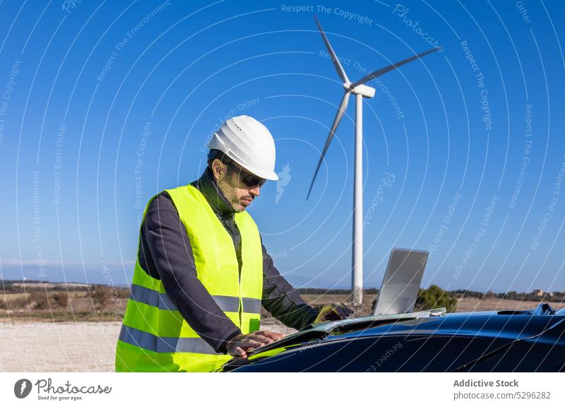 Männlicher Ingenieur, der eine Karte auf der Motorhaube eines Autos untersucht Mann untersuchen Landkarte PKW Kapuze Landschaft Arbeiter Wind Turbine Innovation