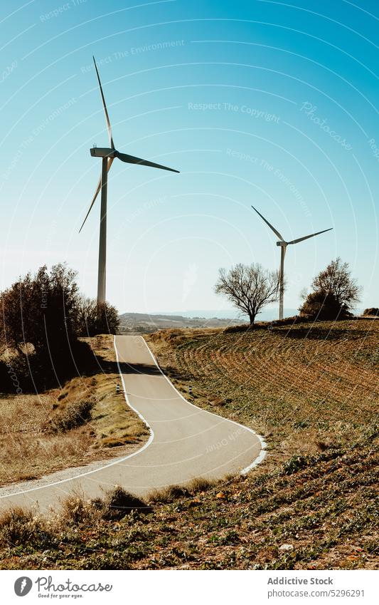 Windmühlen auf einem Feld in der Nähe der Straße Turbine Fahrbahn Landschaft alternativ Energie Blauer Himmel Wolkenloser Himmel Erzeuger Asphalt Ökologie