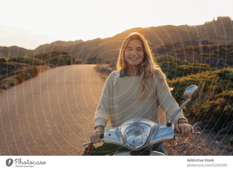 Junge Frau auf Motorroller in der Natur Tretroller Autoreise Fahrzeug Wochenende Route reisen Sonnenuntergang Berge u. Gebirge Glück Lächeln blond jung genießen