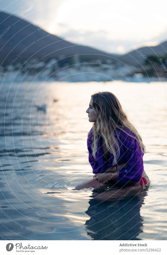 Ruhige junge Frau, die im Meerwasser sitzt und wegschaut MEER Strand Sonnenuntergang verträumt Urlaub Feiertag Erholung bewundern Sommer Meeresufer Natur