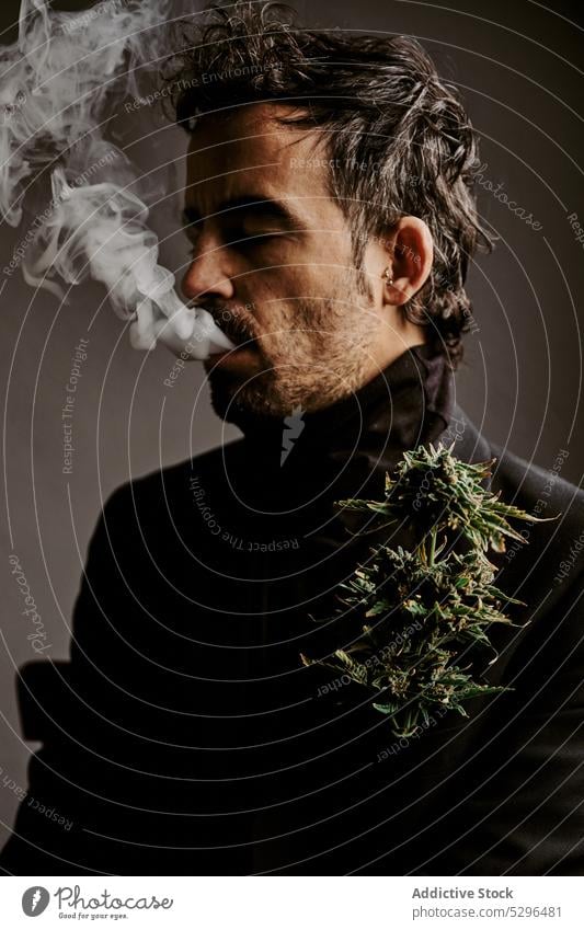 Bärtiger Mann raucht Marihuana in dunklem Raum Rauch Zigarette Raucherin inhalieren ausatmen Habitus Süchtige Medikament Erwachsener männlich dunkles Haar