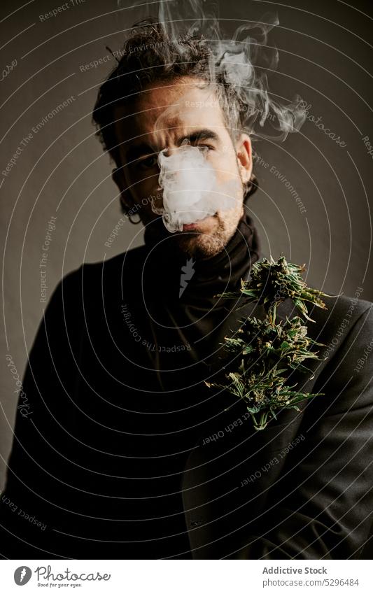 Bärtiger Mann raucht Marihuana in dunklem Raum Rauch Zigarette Raucherin inhalieren ausatmen Habitus Süchtige Medikament Erwachsener männlich dunkles Haar