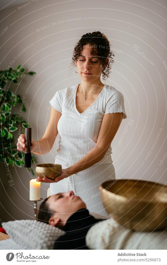 Ruhige Frau bei Klangmassage für Kunden Frauen tibetische Klangschale meditieren Achtsamkeit sich[Akk] entspannen Spa Klient Therapeut Salon Verfahren Masseur