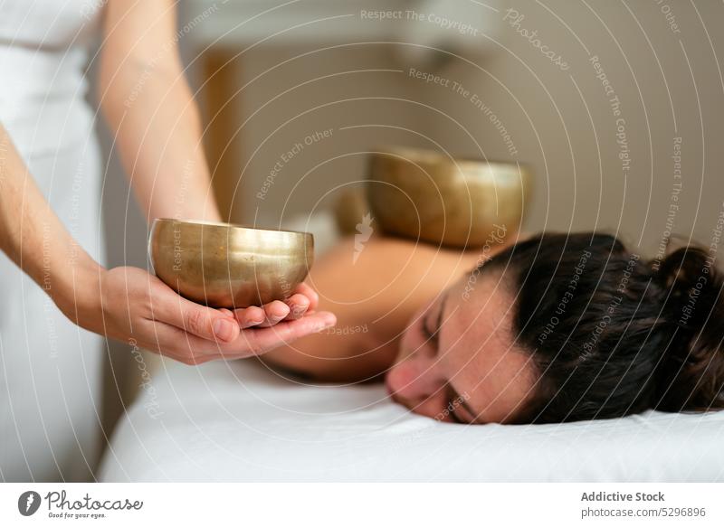 Frau auf der Couch liegend mit geschlossenen Augen während einer Meditationssitzung mit Klangschale Frauen meditieren Therapeut Massage Wiederherstellung Spa