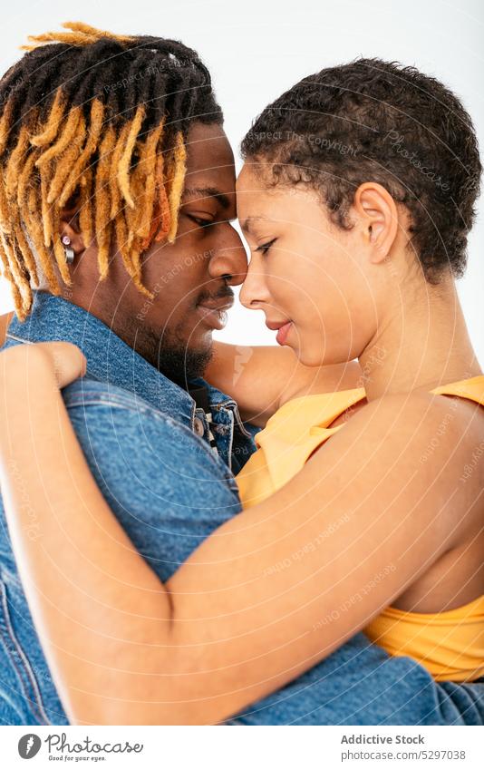 Glückliches ethnisches Paar umarmt auf weißem Hintergrund Freund Freundin Lächeln Partnerschaft Umarmen Umarmung Jeanshose Streetstyle heiter Stil Jeansstoff