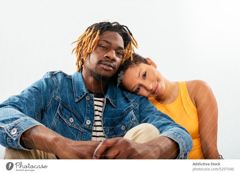 Ein afroamerikanisches Paar sitzt eng beieinander in einem weißen Studio Partnerschaft Freund Freundin Zuneigung Zusammensein Liebe Bonden Streetstyle