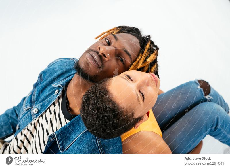 Ein afroamerikanisches Paar sitzt eng beieinander in einem weißen Studio Partnerschaft Freund Freundin Zuneigung Rücken an Rücken Zusammensein Liebe Bonden
