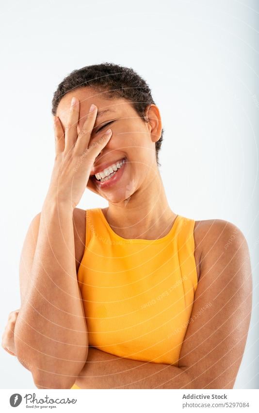 Fröhliche schwarze Frau, die ihr Gesicht bedeckt Lächeln heiter facepalm Deckblatt gestikulieren Stil Glück Studioaufnahme Freude jung Afroamerikaner ethnisch