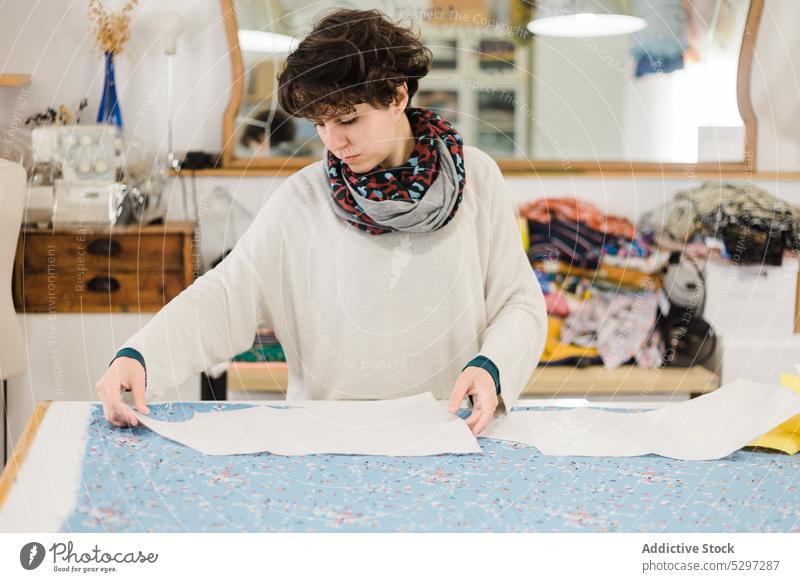 Konzentrierte Frau, die im Atelier ein Muster zum Nähen vorbereitet Näherin Designer Gewebe Damenschneiderin Stoff Werkstatt Textil Schneider kreativ Material