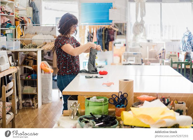 Konzentrierte Frau beim Nähen von Kleidung in einer Werkstatt Näherin Damenschneiderin Muster nähen Atelier Textil Gewebe Stoff Designer Konzentration Fokus