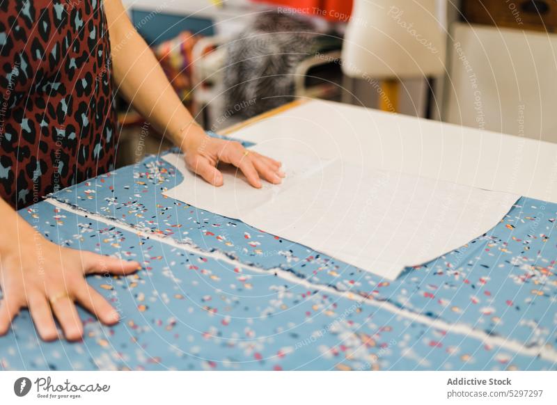 Anonyme Frau, die im Atelier ein Muster zum Nähen vorbereitet Näherin Designer Gewebe Damenschneiderin Stoff Werkstatt Textil Schneider kreativ Material