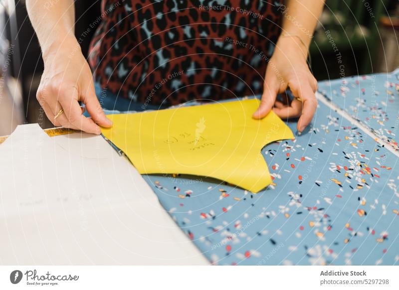 Anonyme Frau, die im Atelier ein Muster zum Nähen vorbereitet Näherin Designer Gewebe Damenschneiderin Stoff Werkstatt Textil Schneider kreativ Material