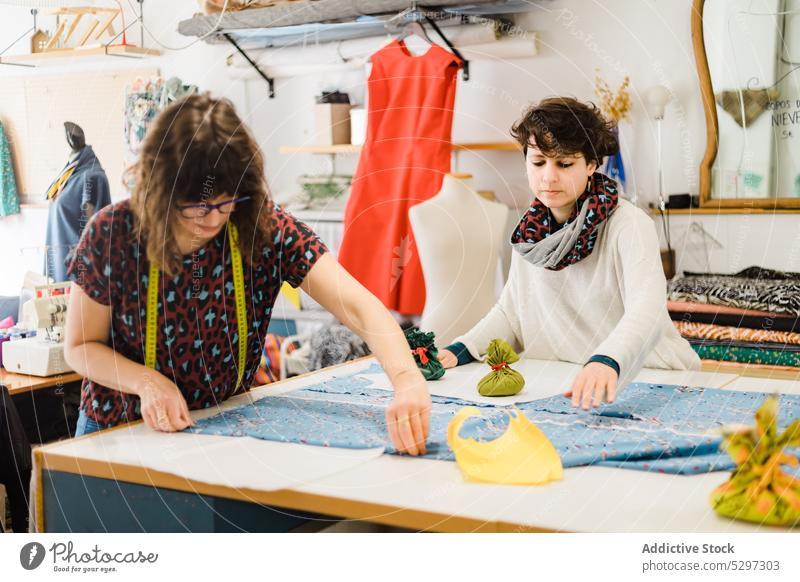 Konzentrierte Frauen arbeiten im Atelier Muster Gewebe Näherin nähen Textil Schneider Kleinunternehmen Fokus Werkstatt Stoff Damenschneiderin Designer Arbeit