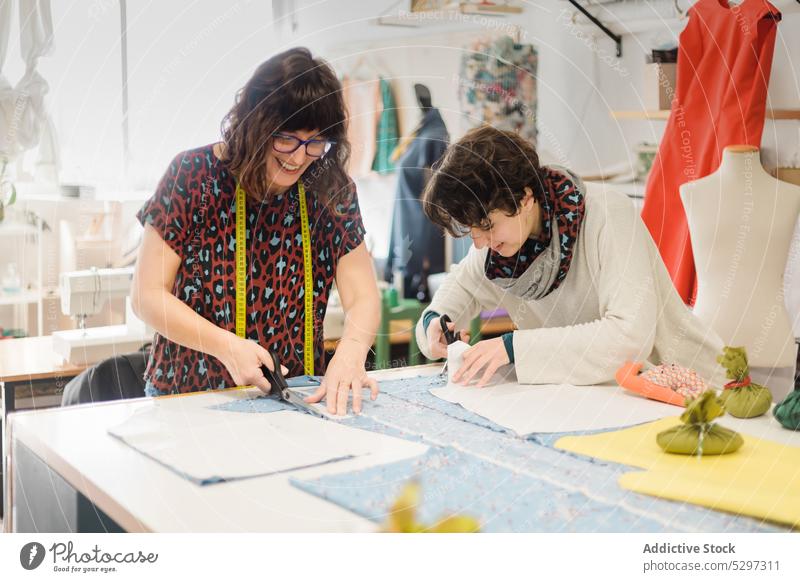 Fokussierte Frauen schneiden Stoff im Atelier Designer Gewebe Näherin geschnitten Damenschneiderin Arbeit Schere Zusammensein kreativ Werkstatt Kollege