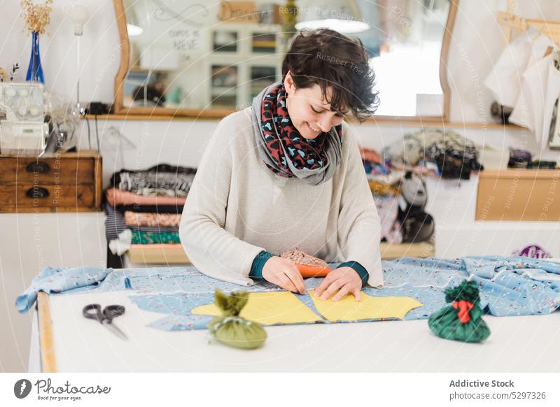 Konzentrierte Frau, die im Atelier ein Muster zum Nähen vorbereitet Näherin Designer Gewebe Lächeln Damenschneiderin Stoff Werkstatt Textil Schneider Glück