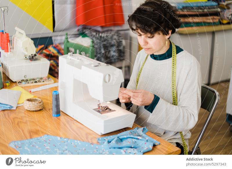 Gezieltes Schneidern an der Maschine im Atelier Frau Näherin Damenschneiderin Klebeband Designer Werkstatt messen Nähmaschine Muster Arbeit professionell