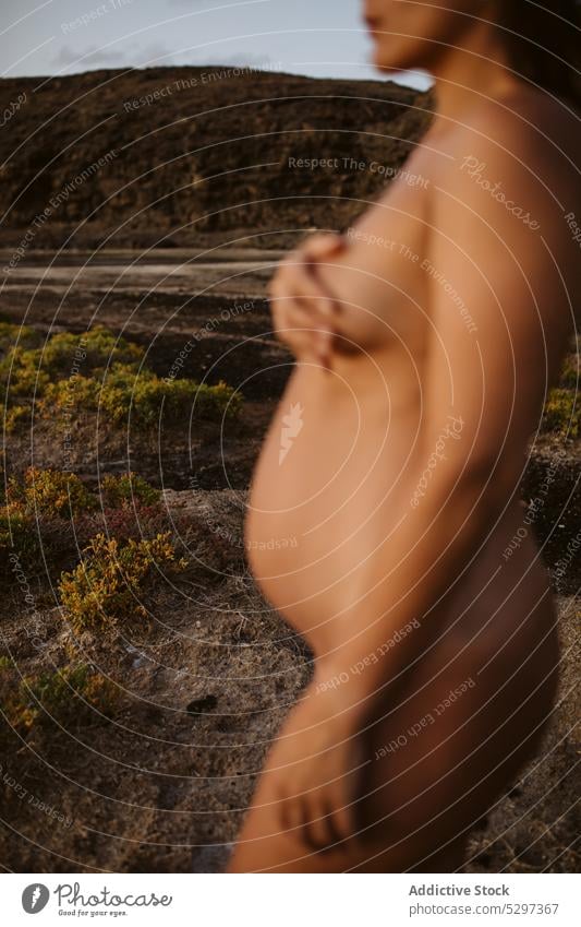 Crop nackte schwangere Frau versteckt Brust in der Natur Sand Bauch Deckung Schwangerschaft Deckbrust oben ohne mütterlich Mutterschaft Körper Umwelt Boden