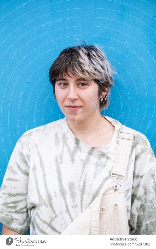 Junge weibliche Lesbe steht in der Nähe von blauen Wand Frau Porträt anlehnen lesbisch Individualität einzigartig Kurze Haare Persönlichkeit modern positiv jung