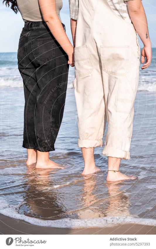 Crop lesbisches Paar hält Hände, während sie im Meerwasser stehen Händchenhalten Wasser MEER Termin & Datum verliebt lgbt Glück jung Spaß Freundin Spaß haben