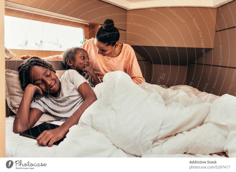 Glückliche schwarze Mutter und Kinder haben Spaß im Bett spielen Lächeln ruhen positiv Wochenende Zusammensein ethnisch Afroamerikaner Eltern Geschwisterkind