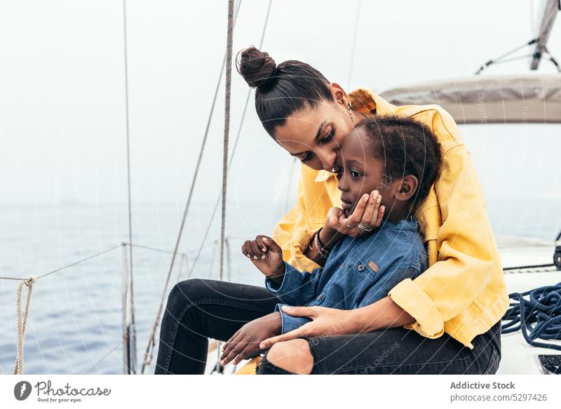 Fröhliche schwarze Frau umarmt ihren Sohn auf einer Jacht Mutter Lächeln Zusammensein Wochenende Umarmung Umarmen Glück Junge Kind lässig gestikulieren MEER