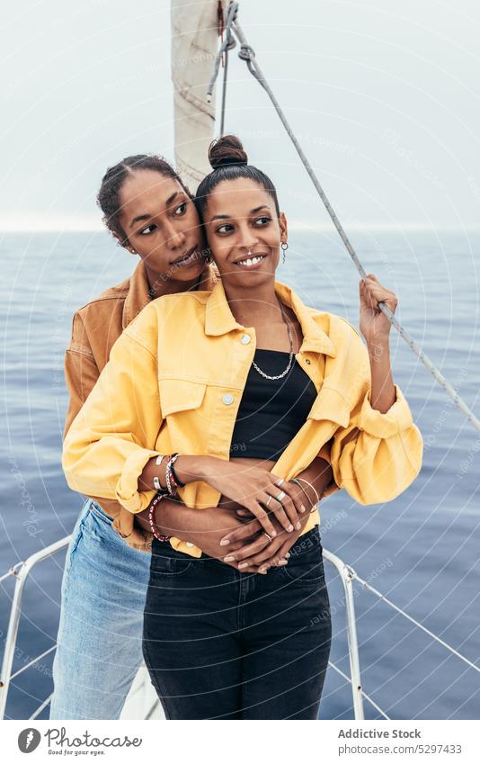 Positive schwarze Freundinnen auf Jacht Frauen Lächeln MEER Umarmung Glück Zusammensein Umarmen lesbisch lgbt Homosexualität heiter ethnisch Afroamerikaner