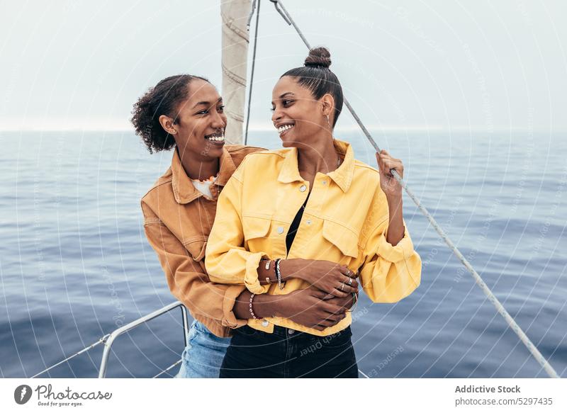 Positive schwarze Freundinnen auf Jacht Frauen Lächeln MEER Umarmung Glück Zusammensein Umarmen lesbisch lgbt Homosexualität heiter ethnisch Afroamerikaner