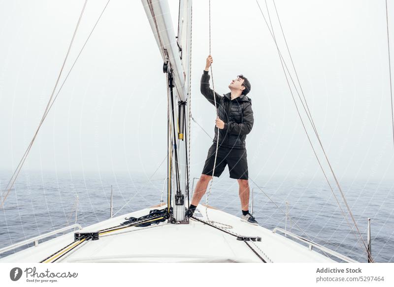 Konzentrierter Mann hisst Segel auf einer Jacht Ausflug Seil ziehen MEER Segelboot Kreuzfahrt Verkehr männlich Gefäße Abenteuer Natur Meer Reise Reisender