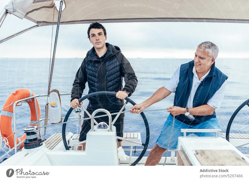 Ernste Männer reiten auf einer Yacht im Meer Mitfahrgelegenheit Jacht MEER Ausflug Wasser selbstbewusst Boot Segel Natur Urlaub reisen Reise männlich Gefäße