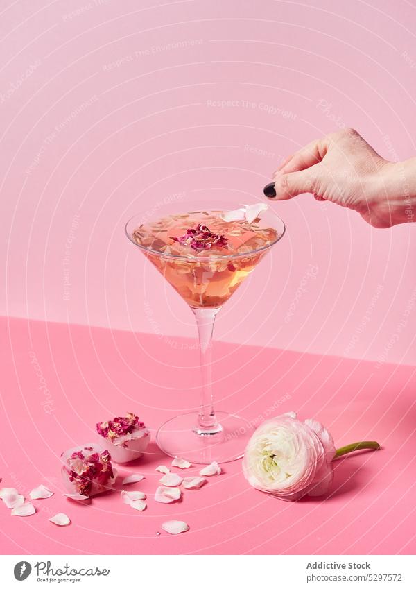 Person, die den Mocktail mit einem Blütenblatt dekoriert rosa Blume Roséwein süß Glas dekorieren geblümt Dekor lecker frisch hell trinken Veranstaltung