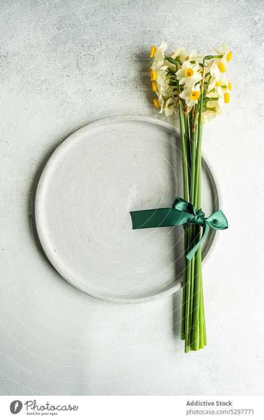 Frühlingshaft gedeckter Tisch mit Narzissen buld Keramik Beton Besteck Abendessen Essgeschirr festlich geblümt Blume Lebensmittel Feiertag Ostern narcisus
