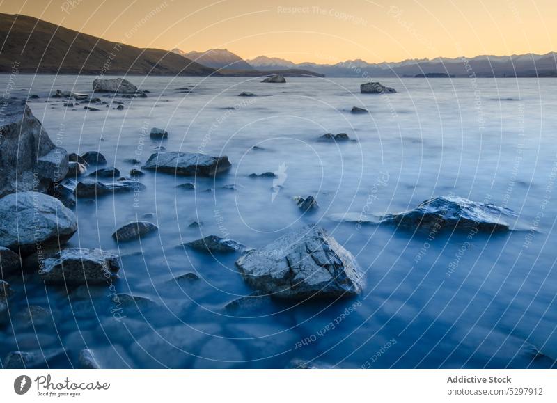 Felsenküste mit Felsen im See bei Sonnenuntergang Stein felsig Ufer Küste Berge u. Gebirge Natur Lake Tekapo Neuseeland malerisch Landschaft Umwelt Wasser Abend