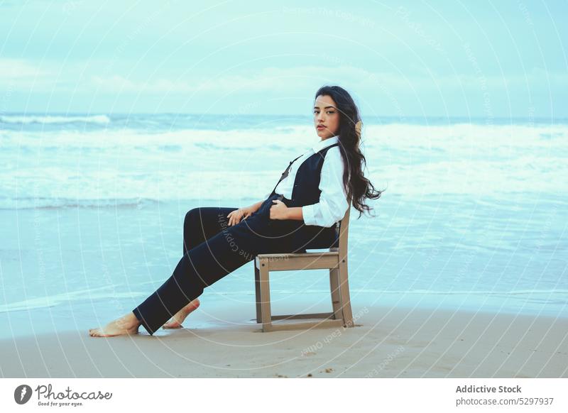 Ruhige Frau sitzt auf einem Stuhl am Meer MEER Strand Meeresufer Sand Seeküste sich[Akk] entspannen ruhen Windstille Küste jung friedlich Stil Wasser Ufer