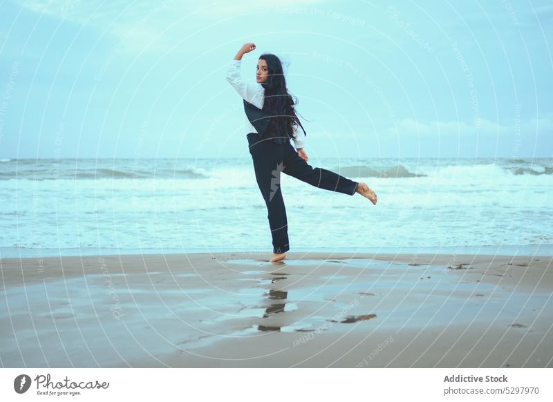 Anmutige Frau balanciert auf einem Bein am Strand MEER Gleichgewicht Sand Meeresufer winken Outfit Seeküste Sommer Küste Ufer Barfuß Wasser nass Stil Harmonie