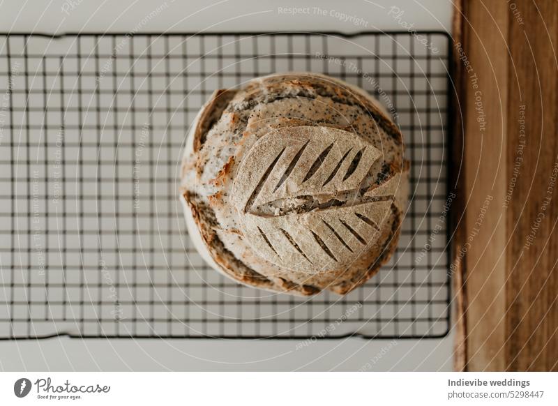 Sauerteigbrot. Selbstgebackenes Brot auf dem Kühlregal. Sanft verschwommener weißer Hintergrund. Gemütliche flache lag mit hölzernen Schneidebrett. Brotlaib