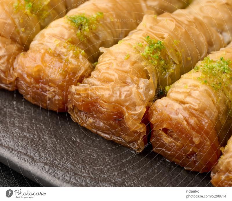Gebackene Baklava-Stücke in Honig und mit Pistazien bestreut auf einem schwarzen Brett Truthahn süß Liebling Lebensmittel Gebäck gebacken traditionell arabisch