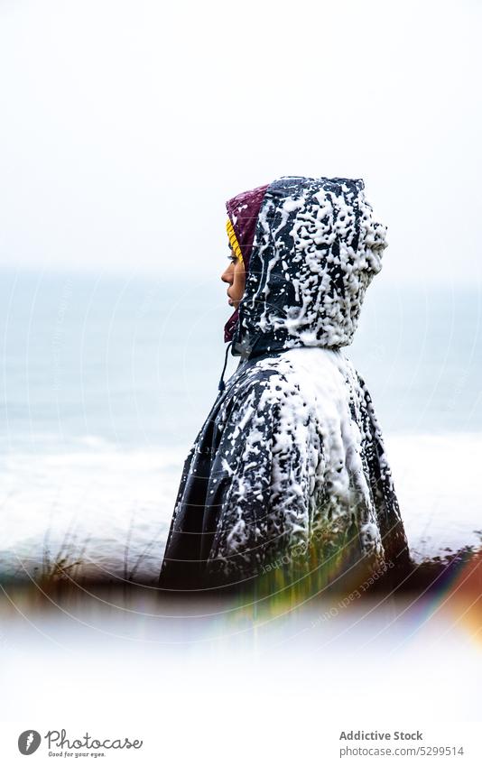 Gesichtsloser Tourist im Regenmantel mit Schnee bedeckt Reisender Kapuzenpulli Urlaub Deckung erkunden bewundern Natur Himmel stürmisch idyllisch Wetter Ausflug