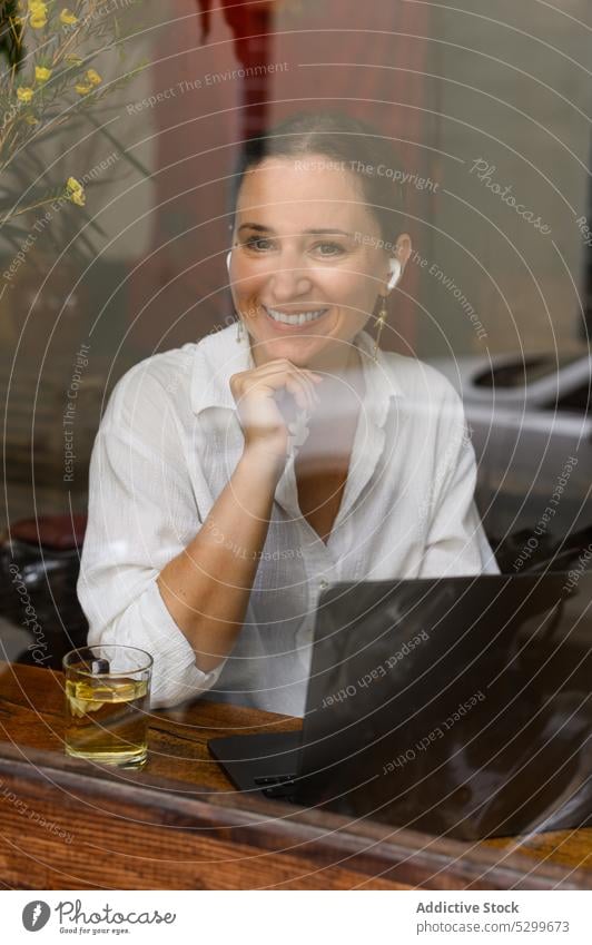 Fröhliche Frau mit drahtlosen Kopfhörern in einem Cafe Laptop abgelegen freiberuflich Café Lächeln Arbeit benutzend positiv heiter Vietnam Drahtlos Glück jung