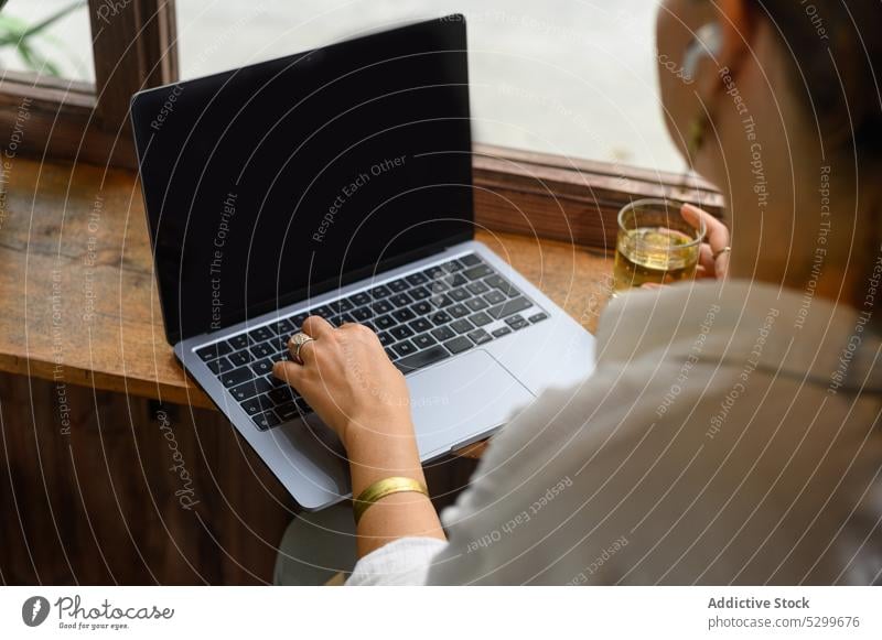 Anonyme Frau tippt auf einem Laptop in einem Cafe abgelegen freiberuflich Café Arbeit Tippen trinken benutzend schwarzer Bildschirm Tee Keyboard Drahtlos