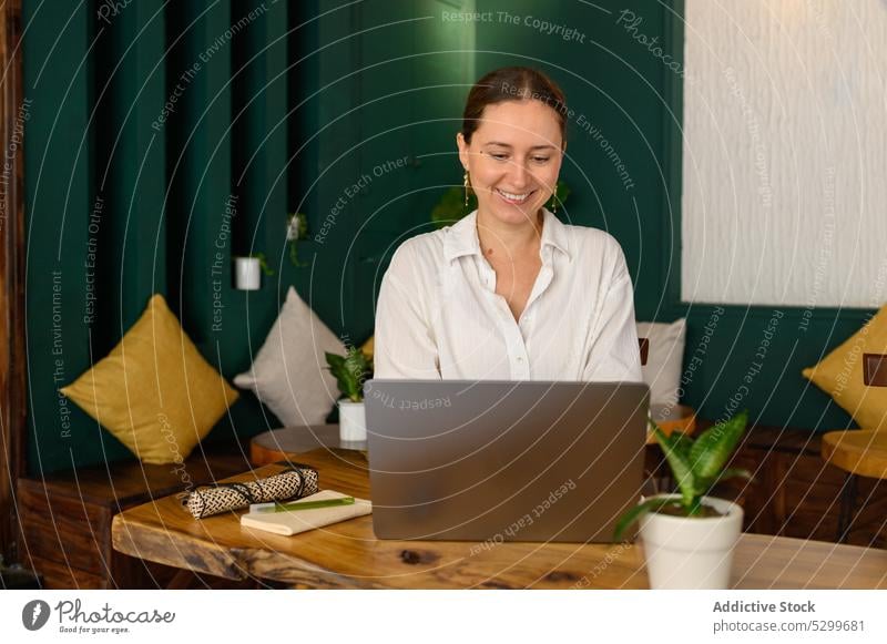 Positive Frau mit Laptop in einem Café freiberuflich Tippen abgelegen Arbeit benutzend Browsen Gerät Vietnam Apparatur Projekt Netbook online Tisch Entfernung