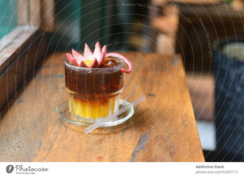 Ein Glas kalt gebrühter Kaffee mit einer Blume oben drauf Getränk brauen trinken Café Saft Erfrischung Stroh Cocktail Tisch Vietnamesen orange Tasse hölzern