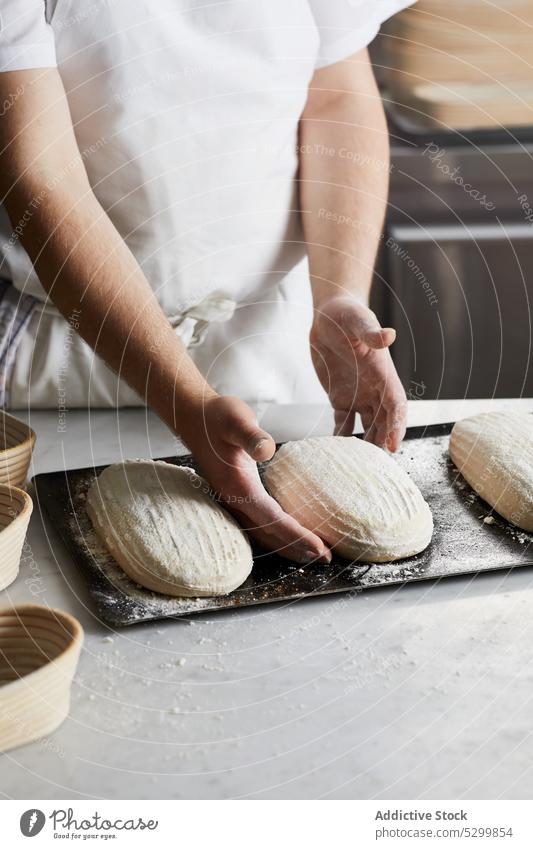 Crop-Bäcker bei der Zubereitung von Sauerteigbrot in der Küche Person Teigwaren Koch Mehl Brot vorbereiten Gärkorb Tisch Bestandteil Gebäck einrichten Handwerk