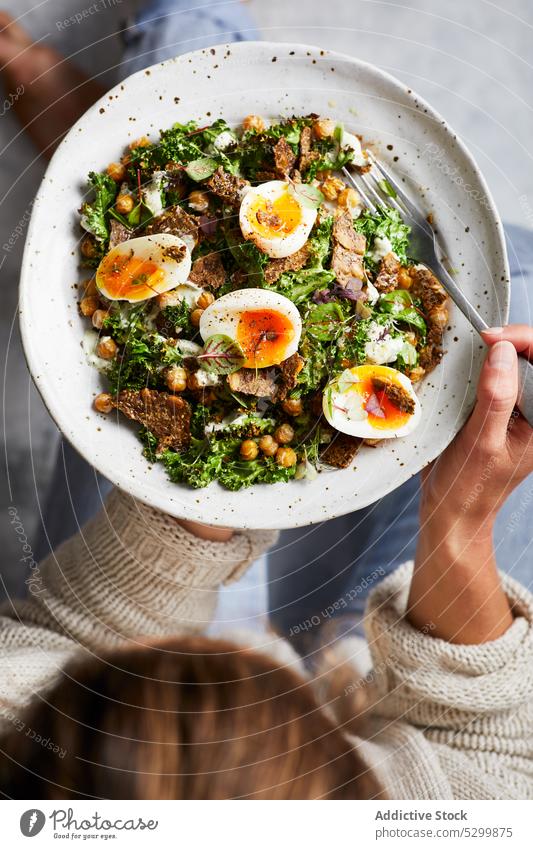 Anonyme Frau isst appetitlichen Salat mit Eiern und Kichererbsen essen Salatbeilage Speise gesunde Ernährung Mittagessen hungrig Gesundheit Lebensmittel Kraut