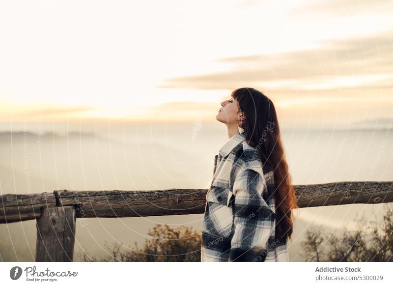 Verträumte Frau steht in der Nähe von Holzzaun in der Natur Sonnenuntergang Reisender Himmel Zaun besinnlich nachdenklich Windstille ruhen Spanien reisen