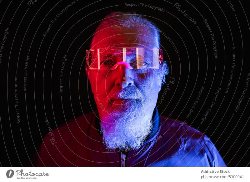 Selbstbewusster älterer Mann mit Brille neonfarbig Hipster Vollbart Porträt ernst Stil selbstbewusst leuchten männlich Senior Licht besinnlich reif hell modern