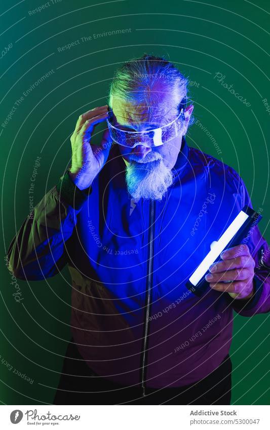 Verblüffter älterer Mann mit Neonlicht neonfarbig Hipster Überraschung erstaunt Tastkopf Vollbart Stil Brille Schock männlich lässig Senior Licht besinnlich