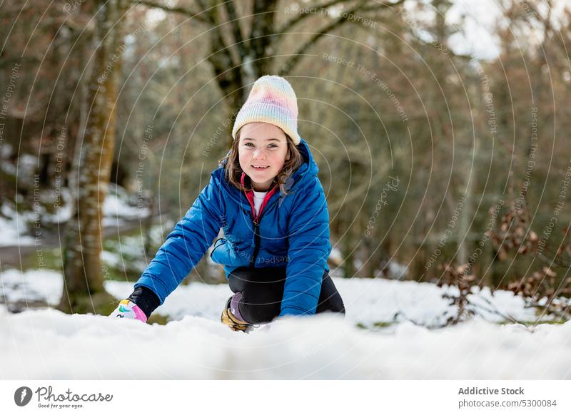 Fröhliches Mädchen spielt mit Schnee spielen Wald Lächeln Winter Glück warme Kleidung Natur kalt Kind Oberbekleidung heiter Saison Hut Freude Spaß Frost Wälder